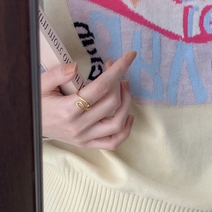 Minimalist gold wavy ring for women shown on hand against a warm cozy background