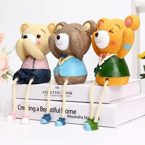 Close-up of three resin bears with dangling rope legs sitting on books home decoration