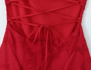 Détail de la robe en dentelle rouge avec broderie florale et laçage au dos