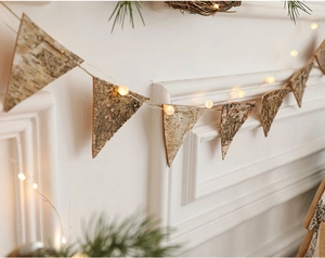 Detail of rustic birch bark triangle bunting banner with warm LED globe string lights