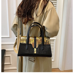 Detail of crossbody bag with black lychee leather and gold snake skin texture flap