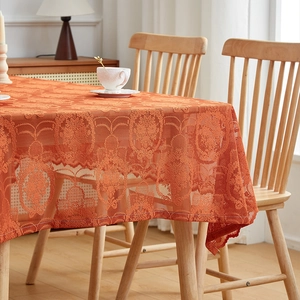 Detail of rust red vintage lace tablecloth with intricate floral patterns and scalloped edges