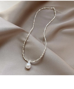 Macro shot of pearl pendant and faceted silver chain on elegant silk background