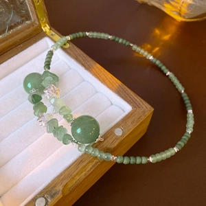 Dettaglio di perle di giada verde e fiori argentati su una scatola di gioielli in legno