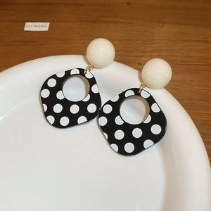 Detailed view of leopard print round earrings with beige beads on a white ceramic tray