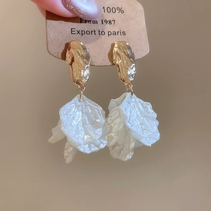 Detailed shot of gold hammered metal and translucent white acrylic petal tassel earrings