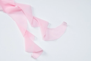 Detailed macro view of pink knitted ribbon fabric texture against a white background