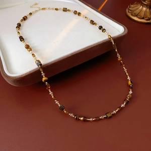 Detail of beaded necklace with faceted tiger eye style stones and gold spacers