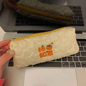Macro detail of quilted pencil case with persimmon embroidery and yellow zipper