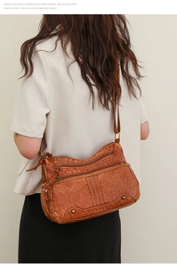 Détail d'un sac bandoulière marron à fermetures éclair multiples sur un mannequin femme