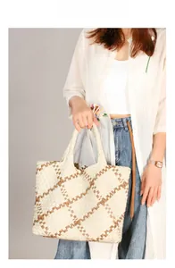 Detail of hand-woven checkerboard tote bag in beige and brown with woven handles
