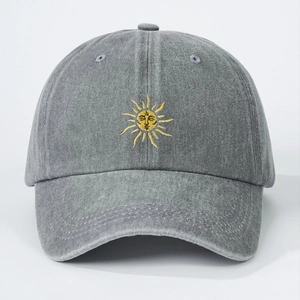 Detail of embroidered yellow sun on a dark gray washed denim baseball cap with clean finish