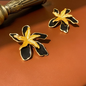 Detailed close-up of double-layer enamel flower earrings in black and gold finish