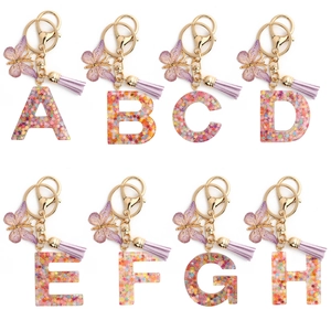 Pink resin alphabet keychains with glitter flowers, purple butterfly and tassel charms