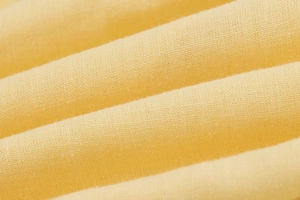 Close-up of yellow linen fabric showing soft texture and natural weaving details