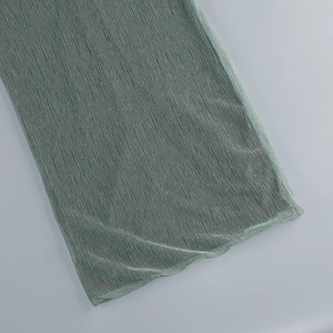 Détail du tissu plissé élégant vert sauge avec texture fine sur la robe à fente latérale