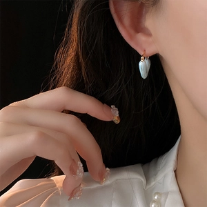 Gros plan d'un modèle portant des boucles d'oreilles cœur dorées avec incrustations bleues