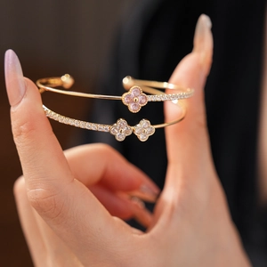 Detailed view of layered four-leaf clover bangles with pink and white zircons
