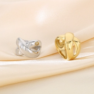 Detailed view of gold and silver cross-twisted rings on elegant champagne silk fabric
