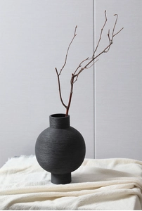 Close-up of black ceramic vase with horizontal brushed texture and wabi-sabi style