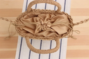 Close-up of khaki woven paper rope beach bag with drawstring fabric lining and top handles
