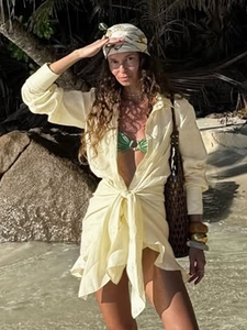 Detail of yellow linen shirt dress with waist tie knot over green bikini for beach vacation