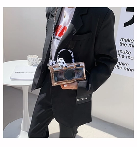 Macro view of camera-shaped crossbody bag with bronze mirror finish and polka dot ribbon