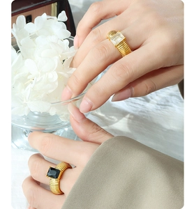 Detail of wide corrugated gold titanium ring featuring a square-cut glass stone on model hand