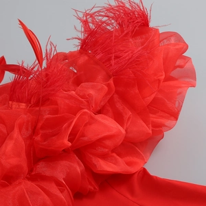 Detail view of red organza ruffles and luxury feather trim on evening dress fabric