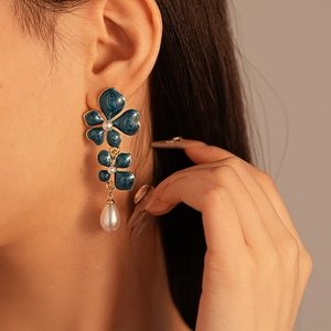 Detail of vintage flower drop earrings with blue enamel and pearls on model