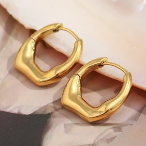 Close-up of irregular 18K gold plated stainless steel hoops on a textured background