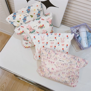 Close-up of four floral rabbit print cotton canvas cosmetic bags with woven labels