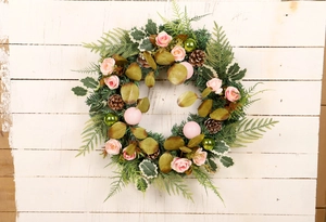 Detail of faux Christmas wreath with pink roses and pine cones on a rustic wood backdrop