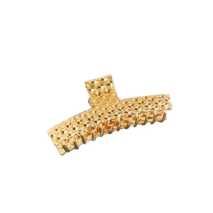 Goldene geometrische Haarspange mit Steppmuster und Metallglanz auf weißem Hintergrund
