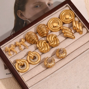 Vue macro de boucles d'oreilles nœuds et géométriques en acier doré avec zircons