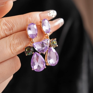 Macro shot of vintage teardrop earrings with purple faceted crystals and gold finish