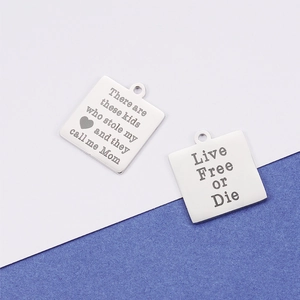 Macro shot of silver stainless steel square pendants with engraved sentimental text
