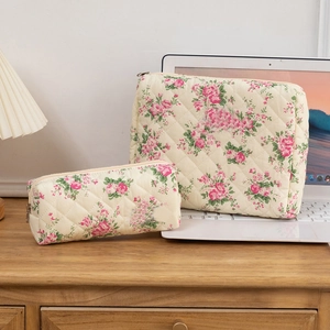 Quilted floral cotton cosmetic bag set with zipper closure on a wooden desk