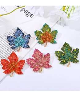 Detailed close-up of luxury rhinestone maple leaf brooches in five vibrant gradient colors