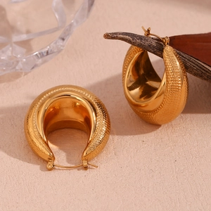 Detail of 18K gold plated peanut earrings with snakeskin texture on warm beige surface