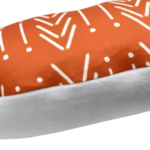 Detailed macro view of orange geometric pattern and soft white plush texture on nursing pillow
