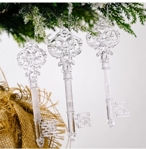 Close-up of three transparent vintage key ornaments hanging on a white Christmas tree branch