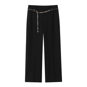 Dettaglio dei pantaloni neri a gamba larga con cintura in pelle e catena in metallo dorato