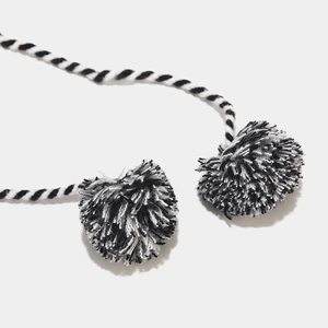 Gros plan sur la maille tricotée noire et blanche avec pompons bicolores et moelleux