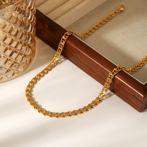 Détail d'un collier en acier inoxydable plaqué or 18K sur un plateau en lin