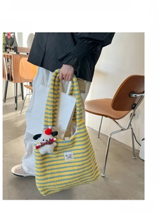 Detail of yellow and blue striped plush tote bag featuring a cute puppy plush charm