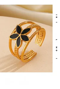 Close-up of 18K gold flower open ring with black enamel petals on silk background