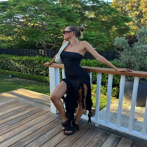 Detail of black strapless dress with ruffled asymmetric hem and high side split design