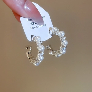Close-up of S925 silver spiral earrings featuring faux pearls and sparkling cubic zirconia
