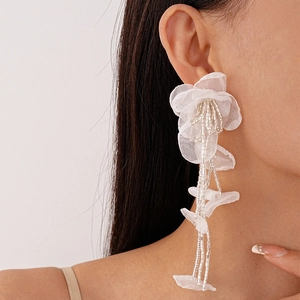 Detailed view of white lace flower earrings with beaded tassels on model's ear